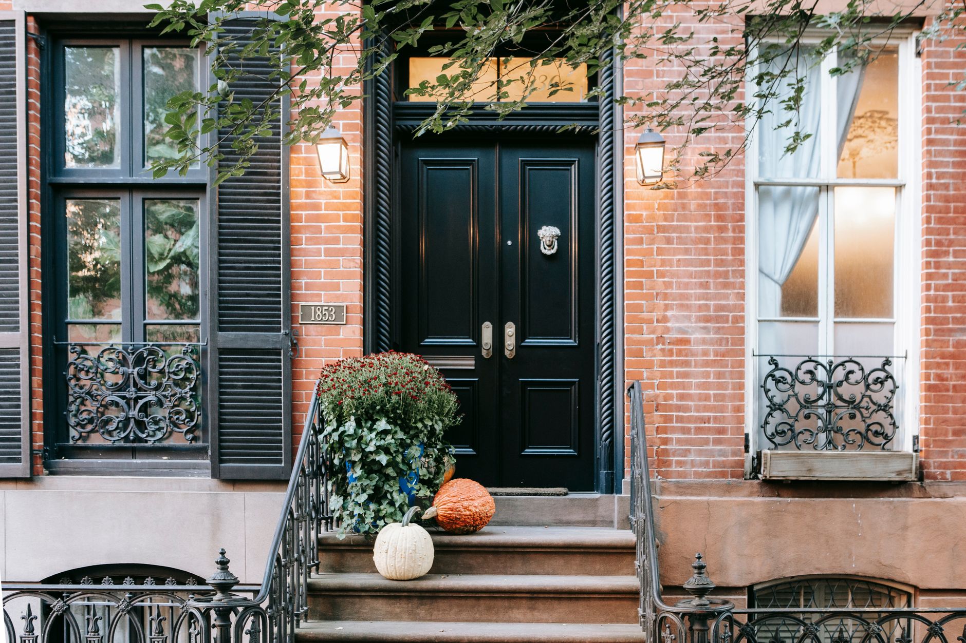 Pumpkins beside the steps of a brick residential entrance in autumn