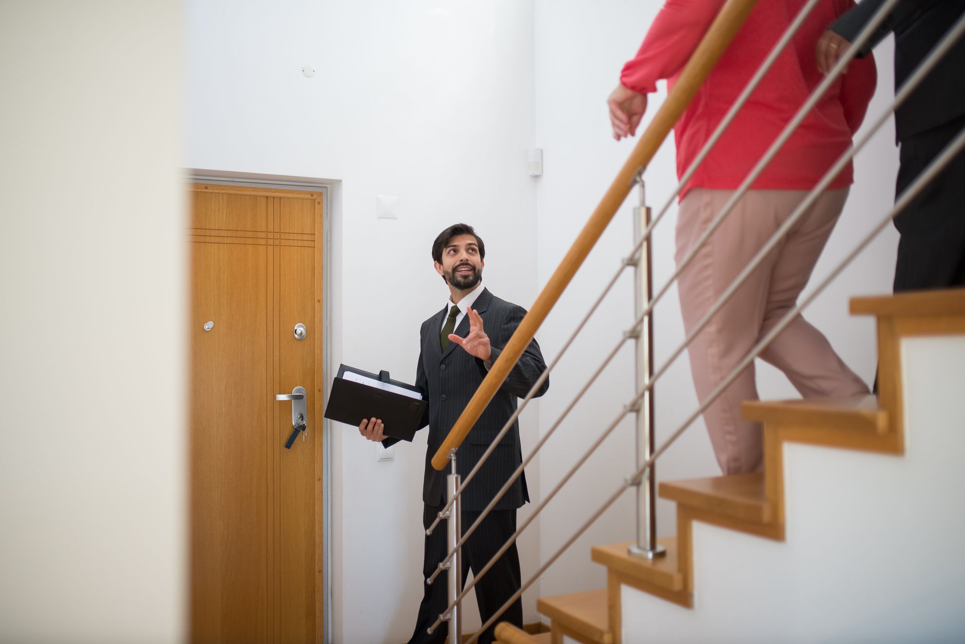 Agent and prospective buyers talking beside a staircase during a home tour