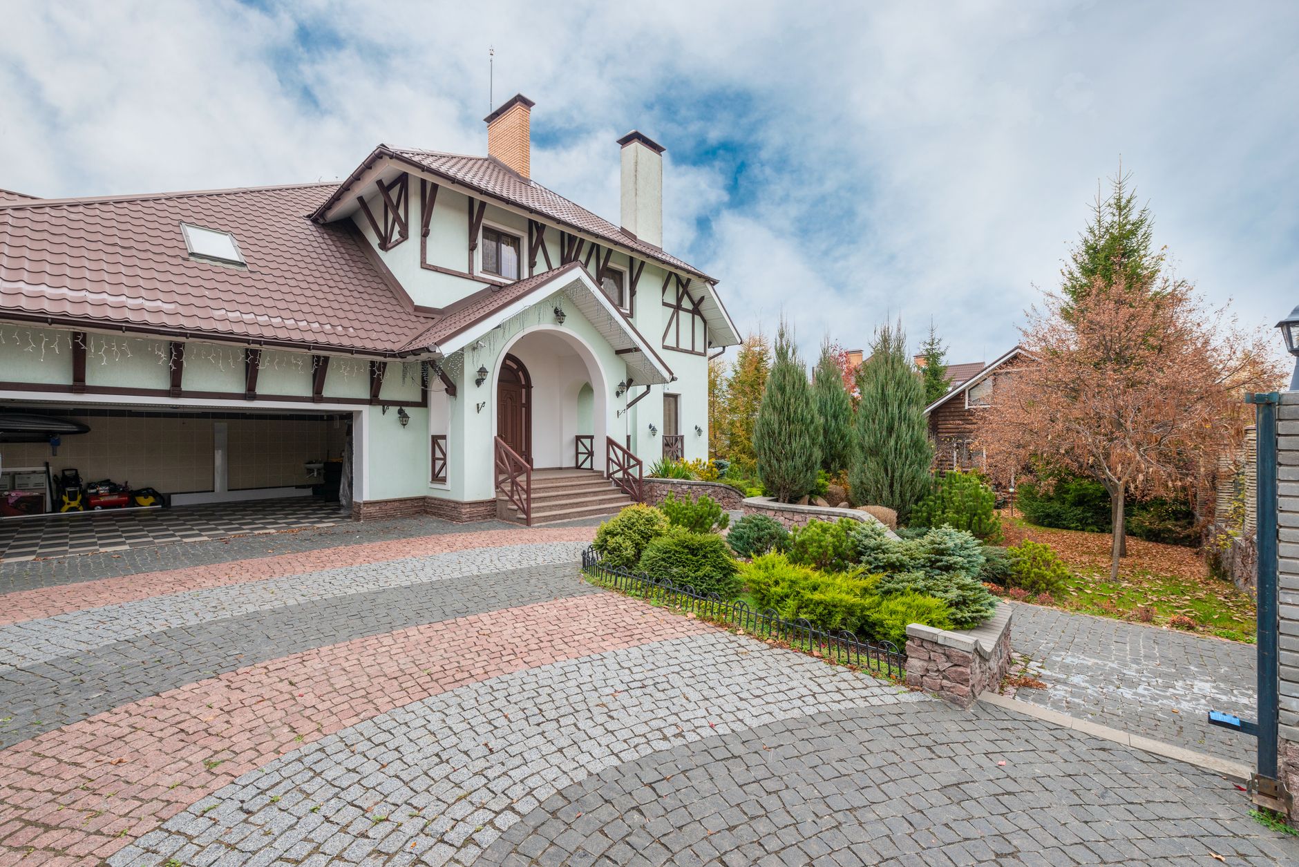 Suburban house with a garden and driveway beneath a cloudy sky