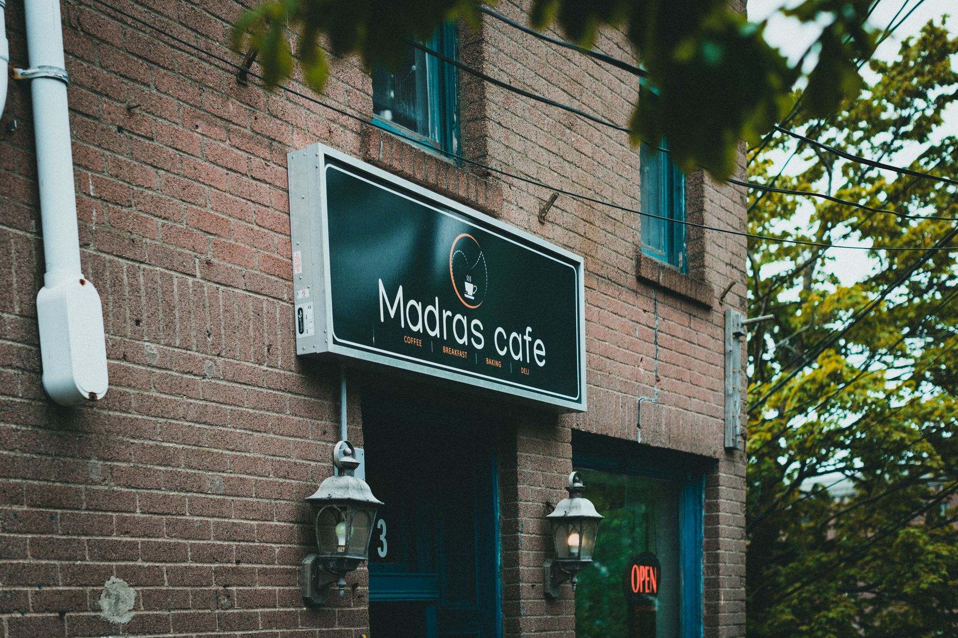 Brick café entrance framed by foliage, illustrative of a neighborhood shopping street