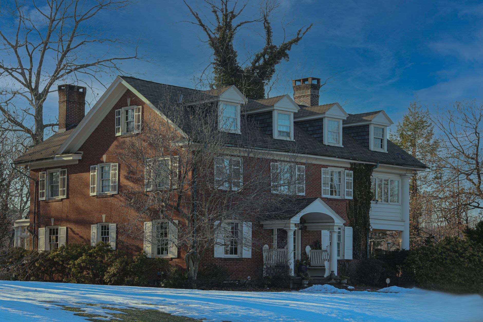 Brick suburban house and snowy yard under a clear winter sky