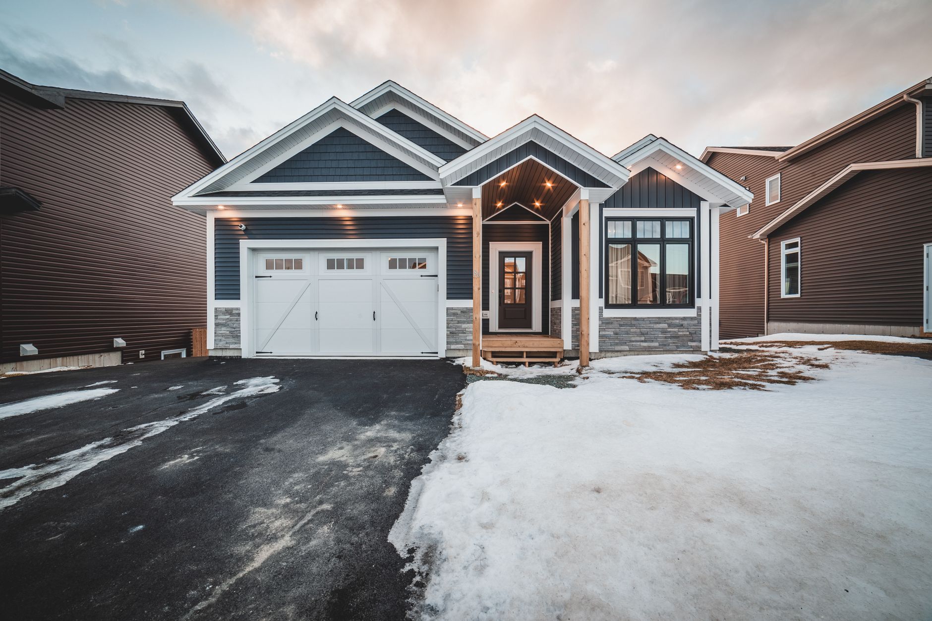 Blue residential house and garage with snow around the property