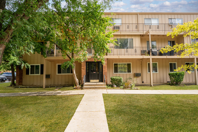 Exterior of the condominium building at 2504 Algonquin Road, Rolling Meadows, with balconies and a walkway to the entrance