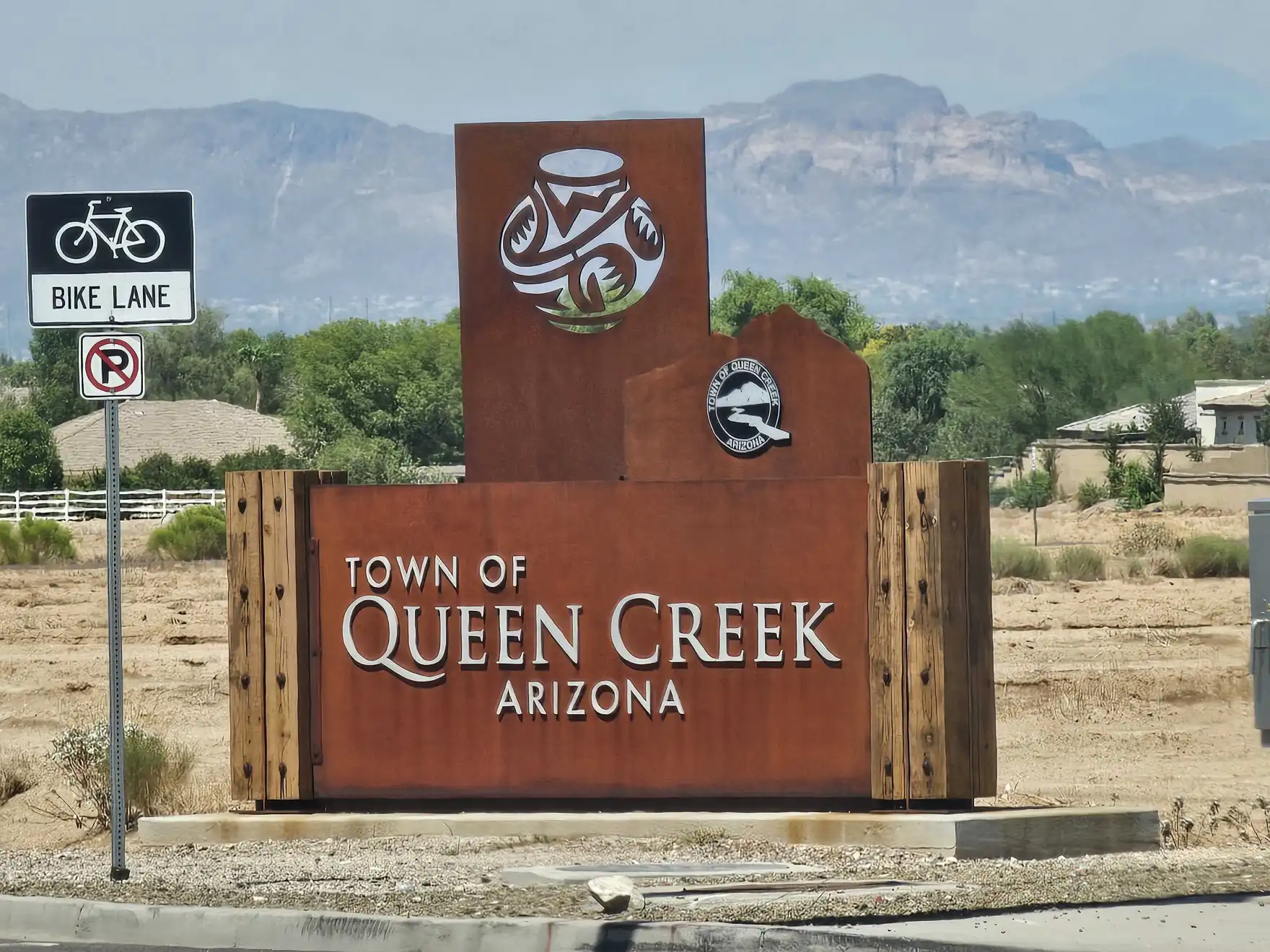 Town of Queen Creek welcome sign with desert landscape and mountains behind it