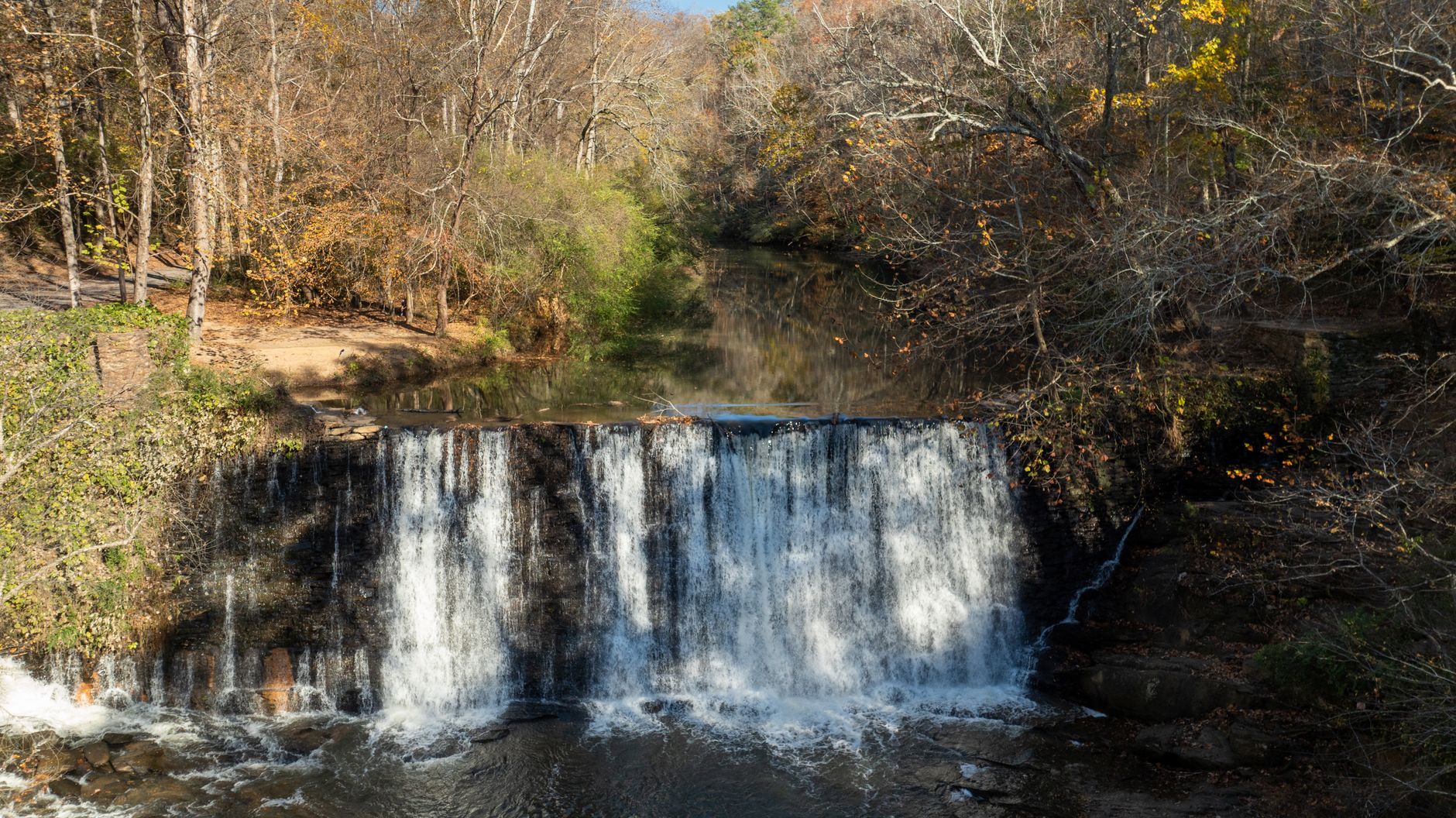 Roswell Mill waterfall surrounded by autumn trees